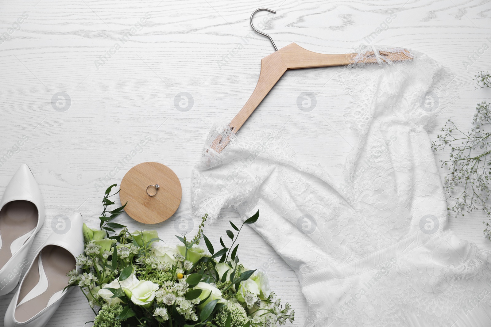 Photo of Beautiful wedding dress, shoes, engagement ring and flowers on white wooden background, flat lay