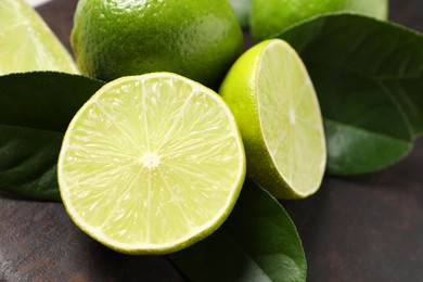 Fresh ripe limes and green leaves on black board, closeup