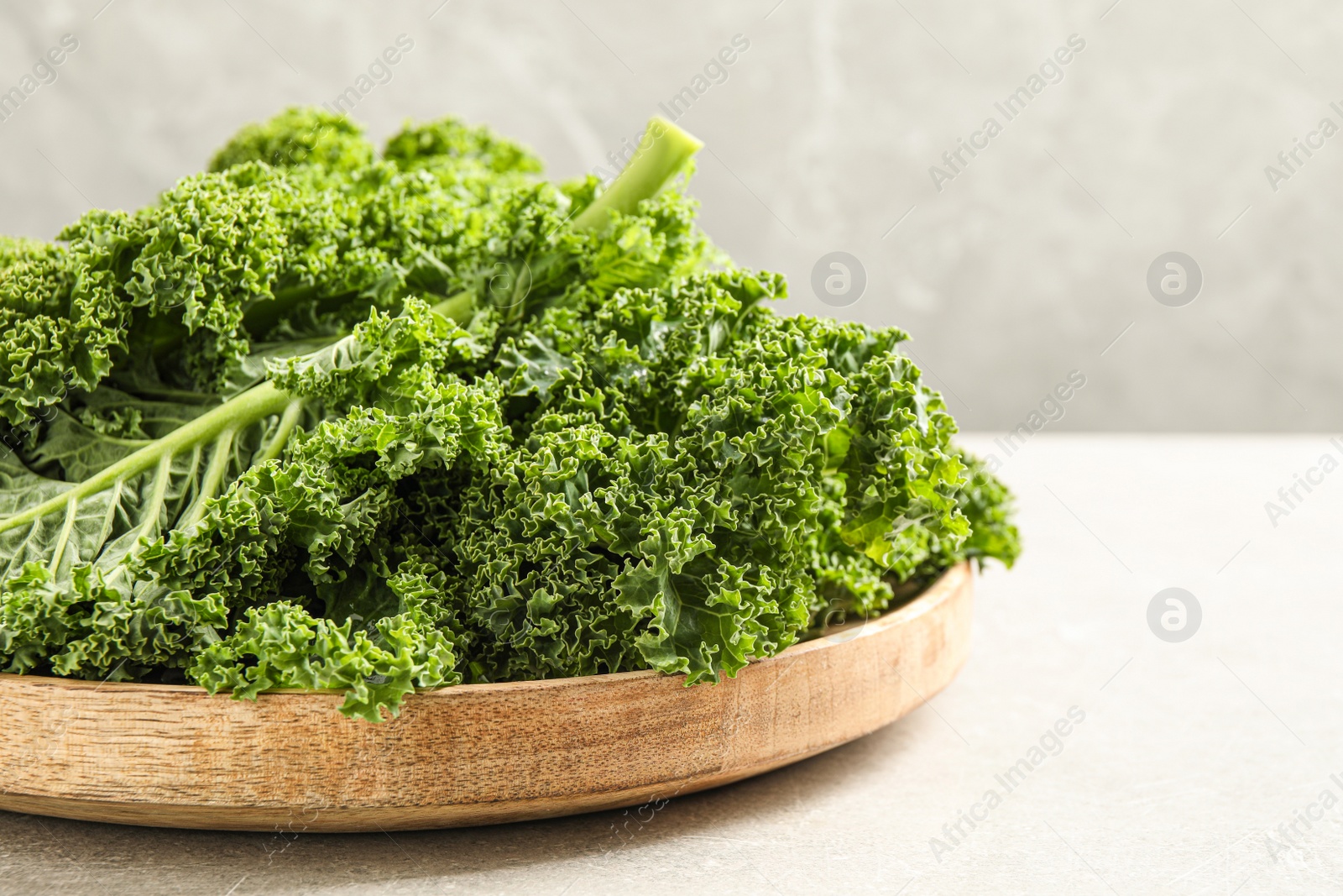 Photo of Fresh kale leaves on light grey table, closeup