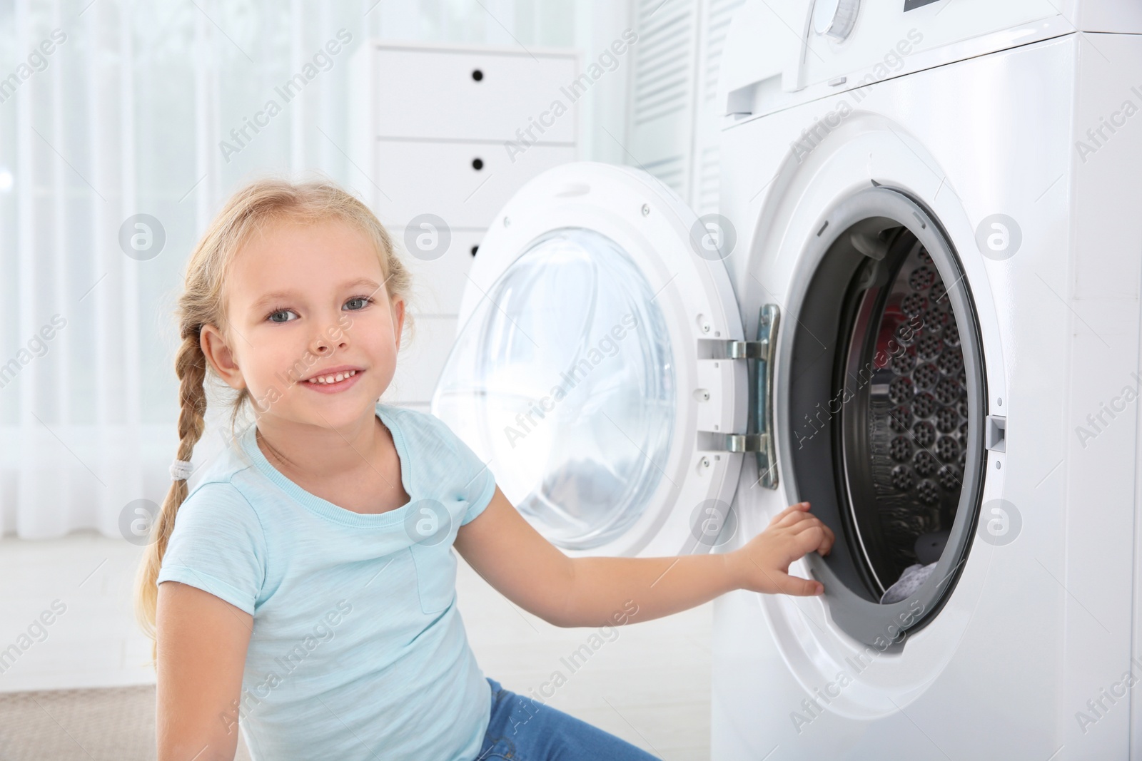 Photo of Adorable little girl doing laundry at home