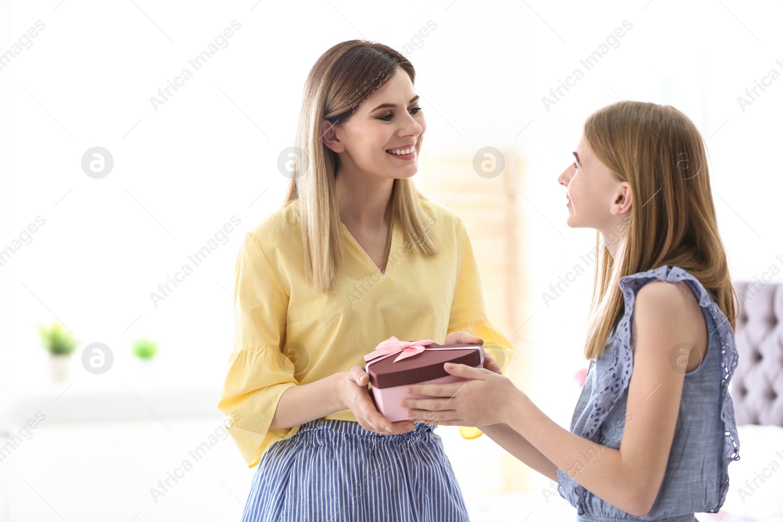 Photo of Teenage daughter congratulating happy woman on Mother's Day at home