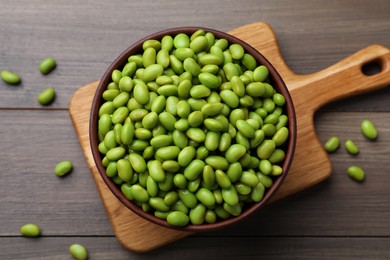 Photo of Bowl of delicious edamame beans on wooden table, flat lay