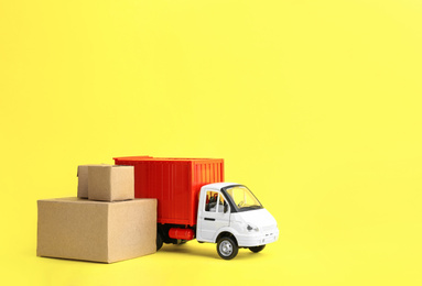 Truck model and carton boxes on yellow background, space for text. Courier service