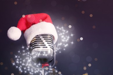 Image of Retro microphone with Santa hat on dark background, space for text. Christmas music