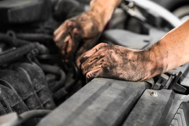 Photo of Dirty mechanic fixing car, closeup of hands