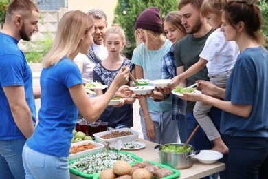 Photo of Volunteers serving food for poor people outdoors