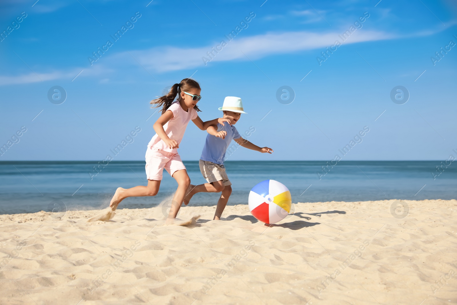 Photo of Cute little children playing with inflatable ball on sandy beach