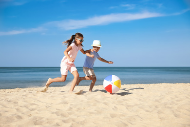 Photo of Cute little children playing with inflatable ball on sandy beach