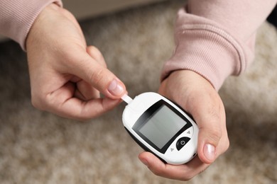 Diabetes test. Man with glucometer on blurred background, closeup