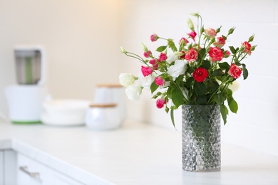 Photo of Vase with beautiful flowers on white countertop in kitchen, space for text