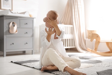 Young mother with her little baby sitting on floor at home