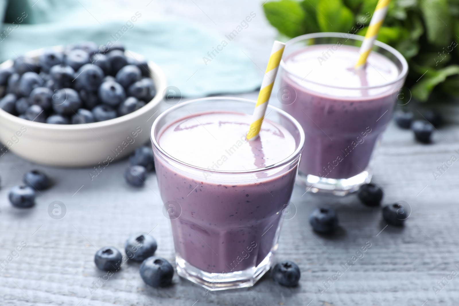 Photo of Freshly made blueberry smoothie on grey wooden table
