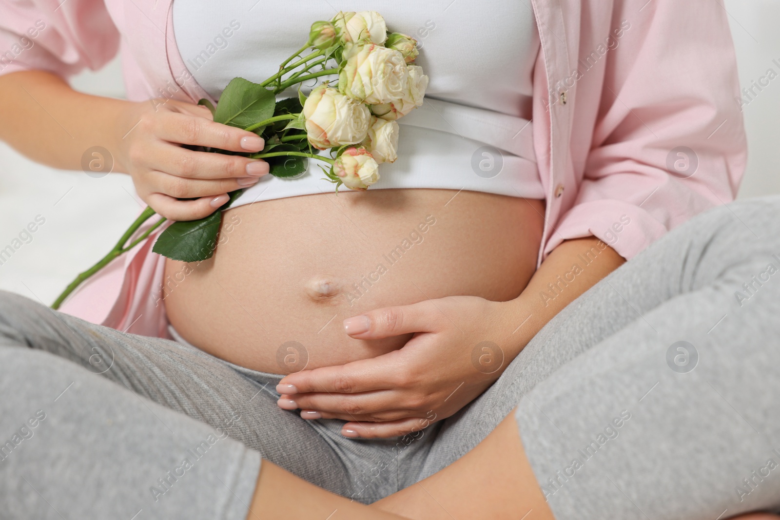 Photo of Pregnant woman in pink shirt with roses, closeup