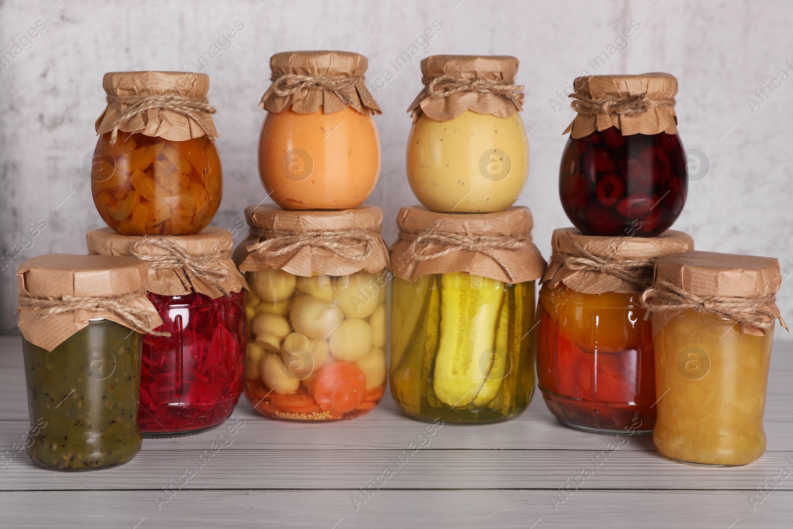 Photo of Many glass jars with different preserved products on wooden table