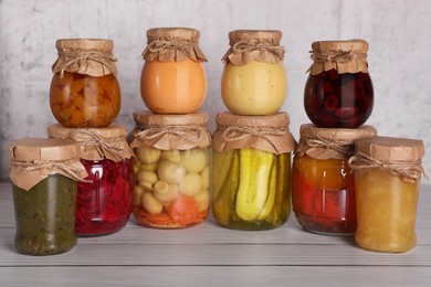 Many glass jars with different preserved products on wooden table