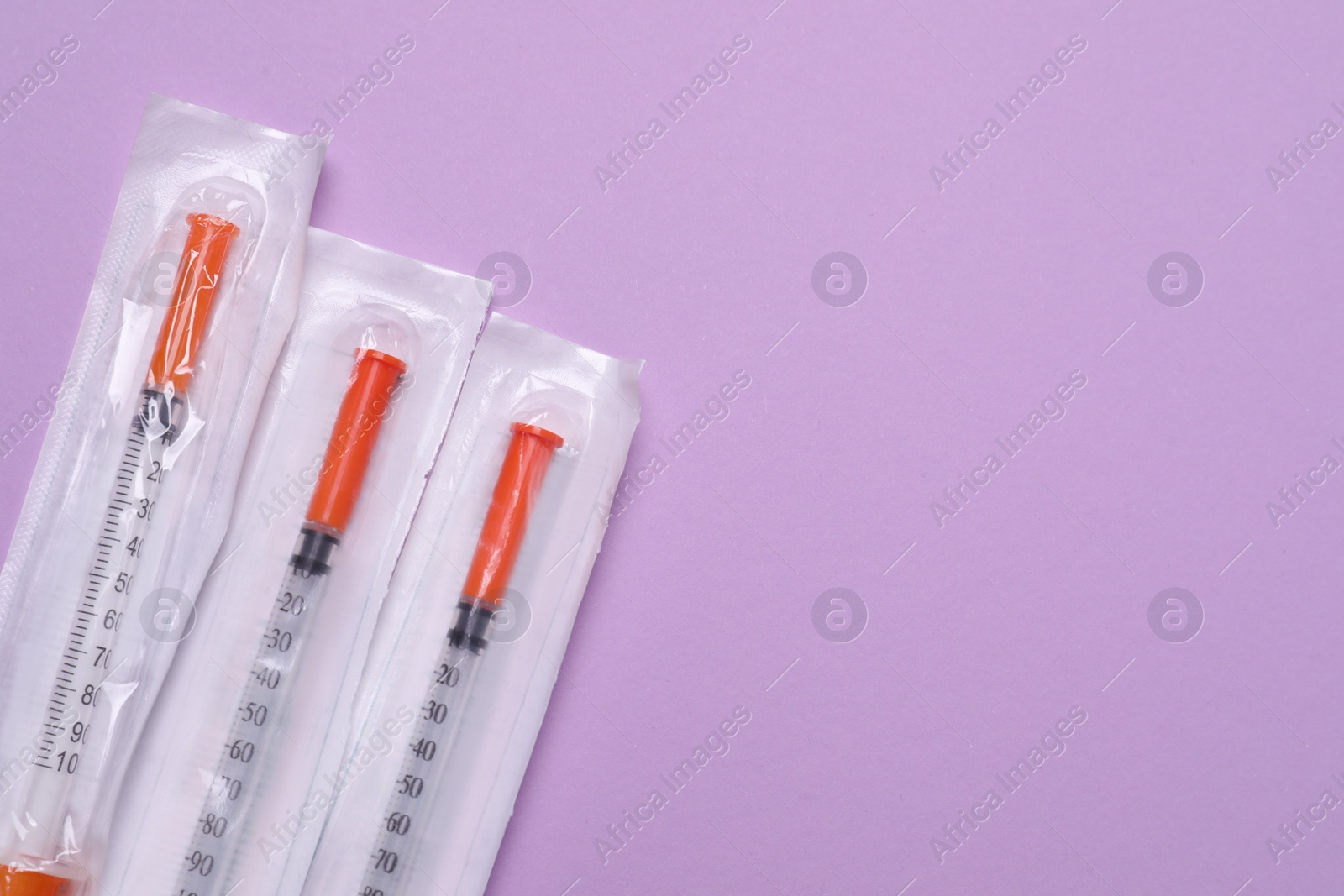Photo of Packed disposable syringes on violet background, flat lay. Space for text