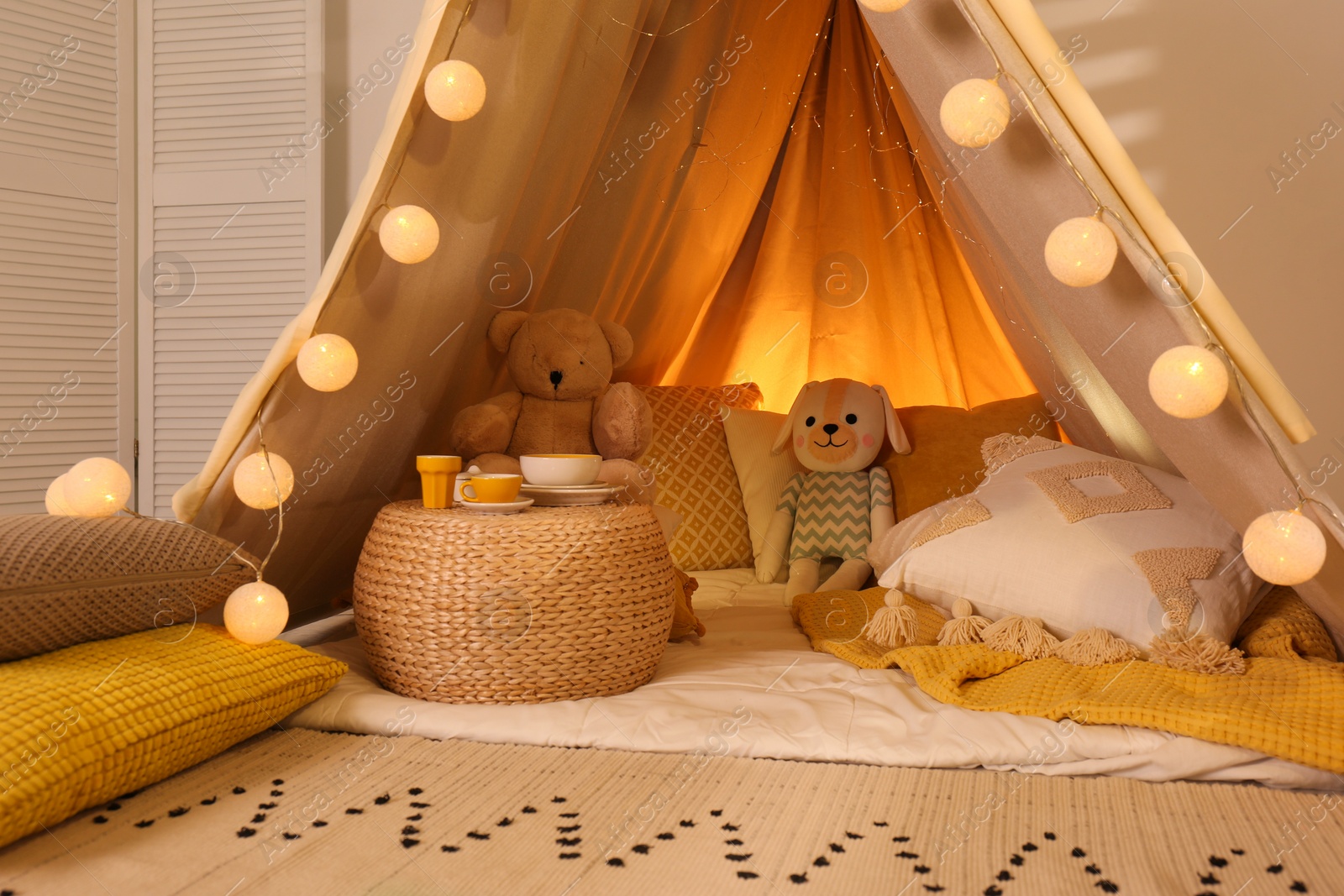 Photo of Play tent with toys and pillows indoors, closeup. Modern children's room interior