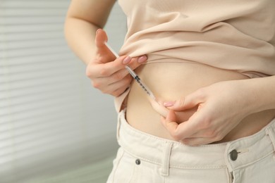 Photo of Diabetes. Woman making insulin injection into her belly indoors, closeup