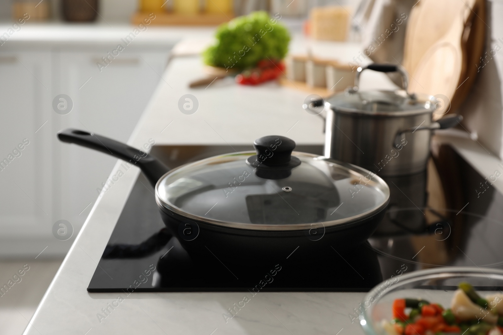 Photo of Frying pan with lid on cooktop in kitchen