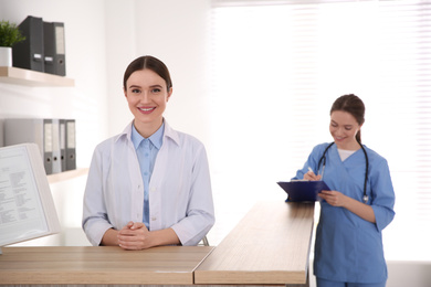 Portrait of female doctor at counter in modern clinic