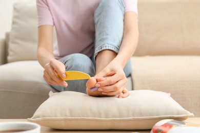 Photo of Woman giving herself pedicure at home, closeup