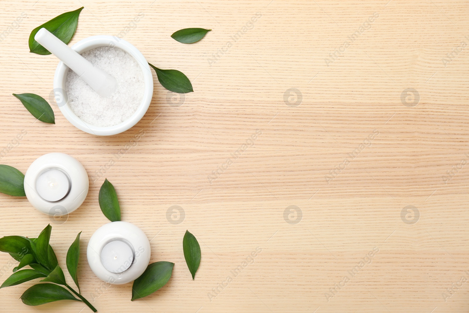 Photo of Bowl with sea salt and candles on wooden background