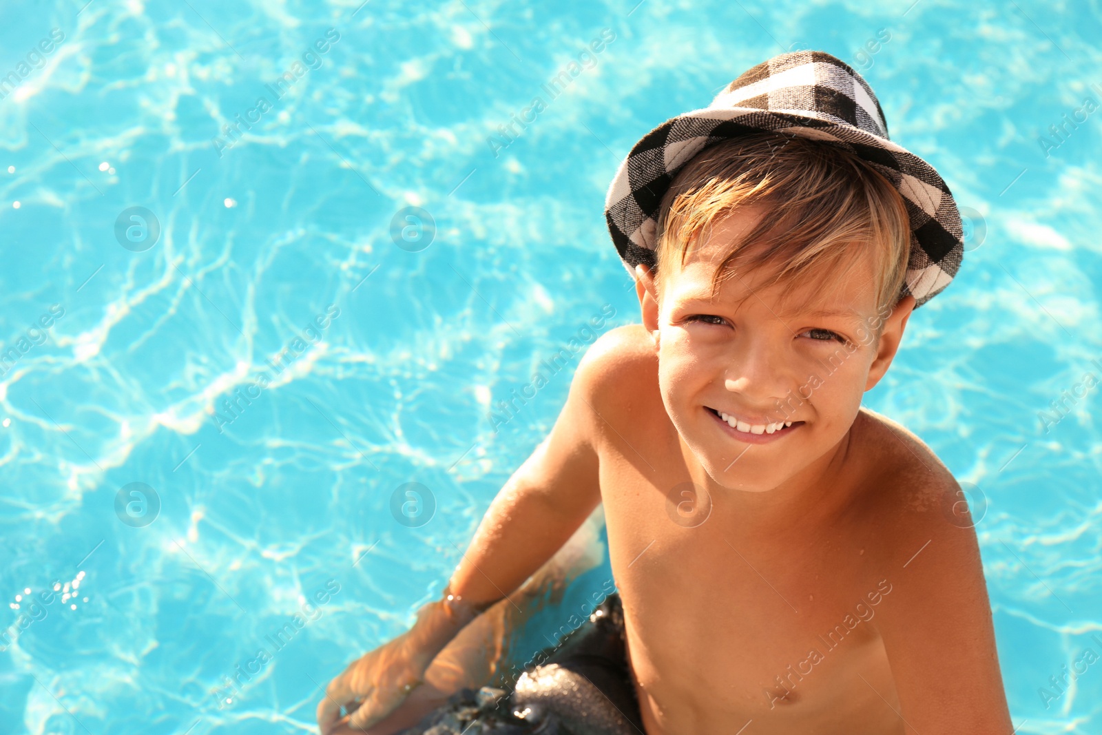 Photo of Happy cute boy with hat in swimming pool