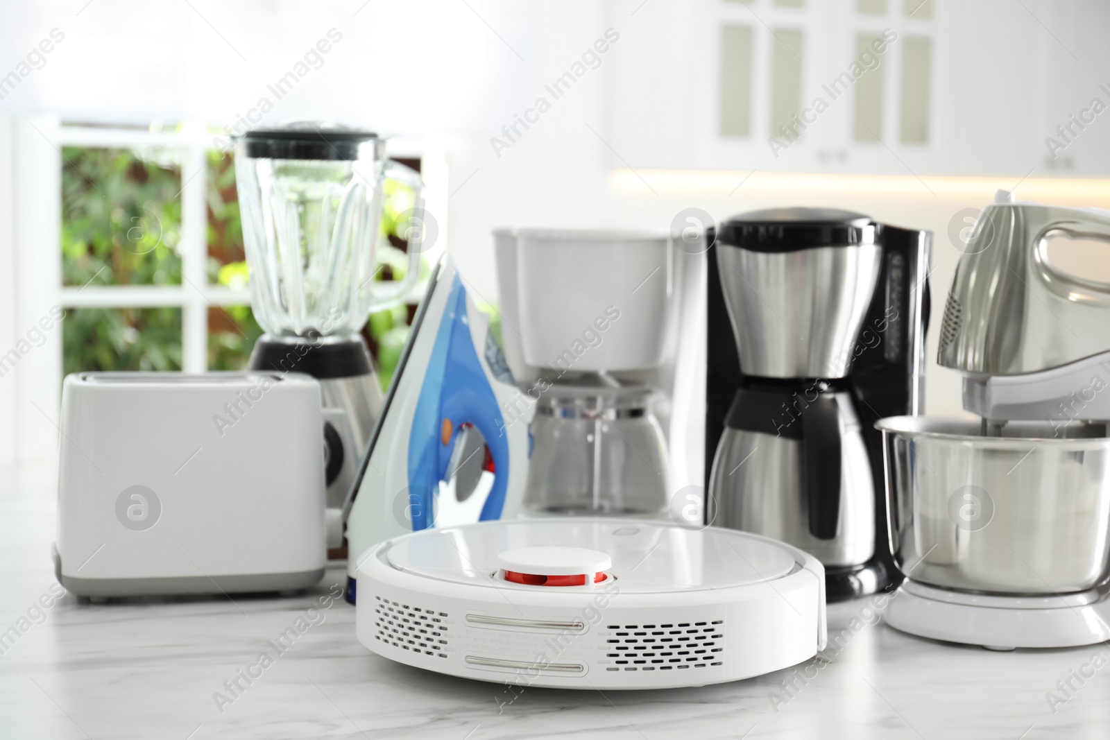 Photo of Set of modern home appliances on white marble table in kitchen