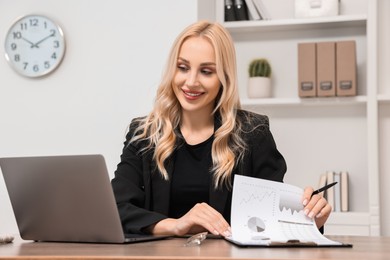 Photo of Happy secretary working with document at table in office