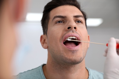 Photo of Doctor taking sample for DNA test from man in clinic