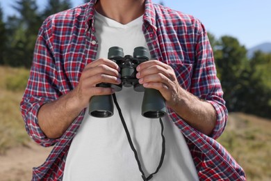 Man with binoculars outdoors on sunny day, closeup