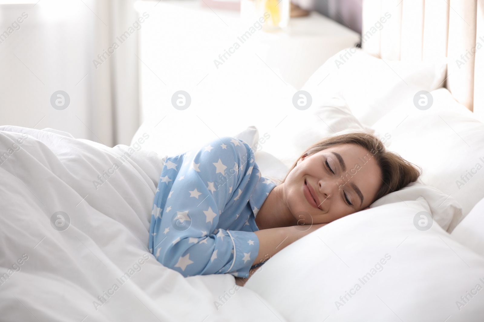 Photo of Young woman sleeping on comfortable pillow in bed at home