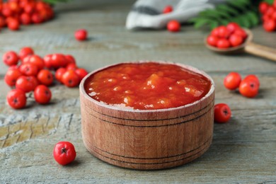 Photo of Delicious rowan jam in wooden bowl on table