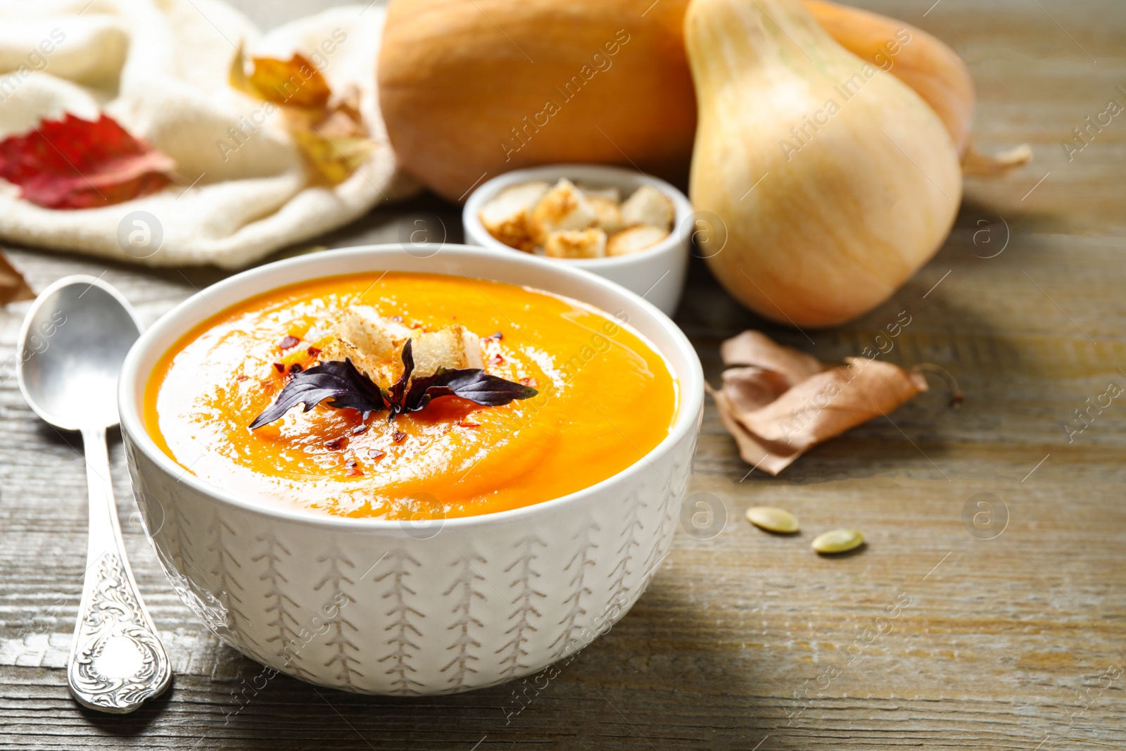 Photo of Delicious pumpkin soup in bowl on wooden table