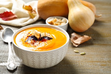 Delicious pumpkin soup in bowl on wooden table