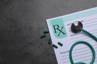 Photo of Medical prescription form, stethoscope and pills on dark grey table, flat lay. Space for text