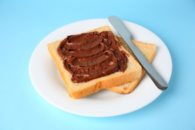 Photo of Tasty toast with chocolate paste on light blue background