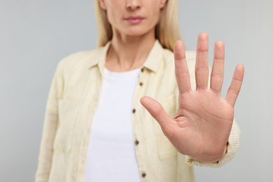Photo of Woman showing stop gesture on grey background, closeup