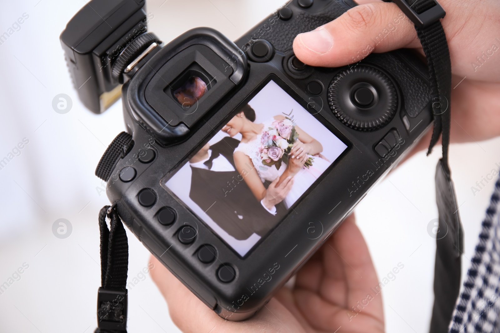 Photo of Professional photographer holding camera with lovely wedding couple on display, closeup