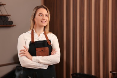 Photo of Professional hairdresser wearing apron in beauty salon, space for text