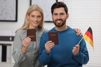 Immigration. Happy couple with passports and flag of Germany indoors