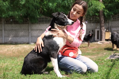 Photo of Female volunteer with homeless dog at animal shelter outdoors