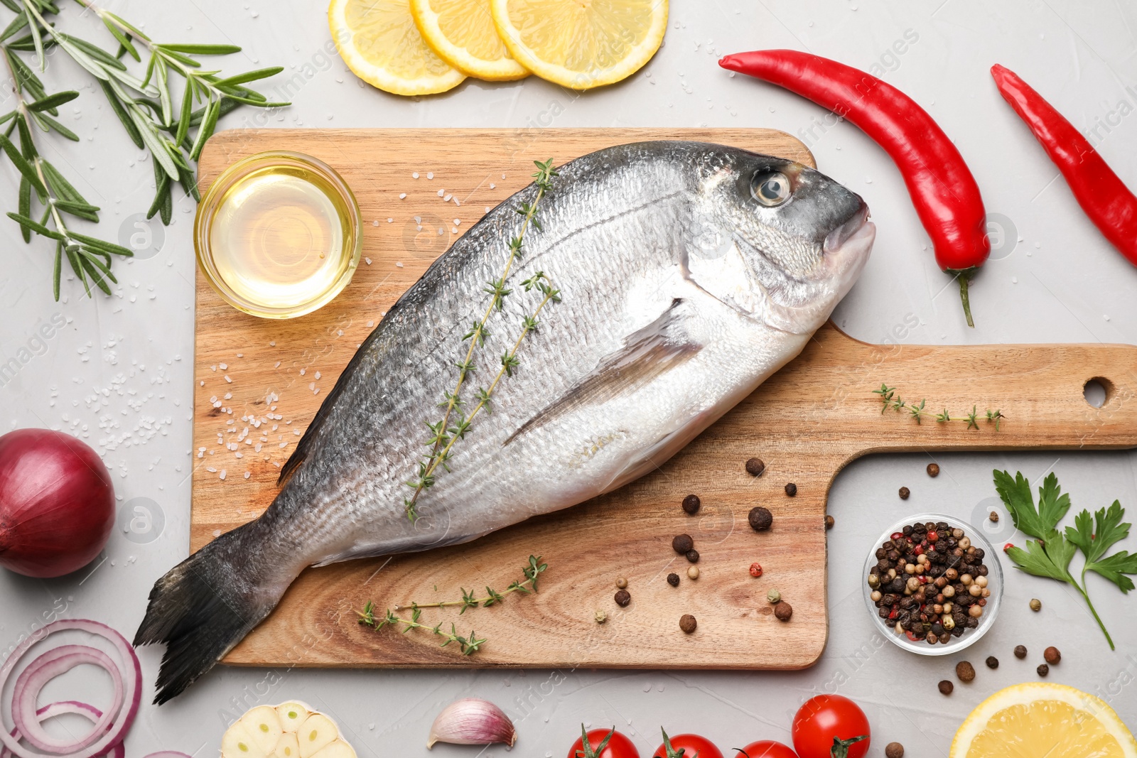 Photo of Flat lay composition with fresh raw dorado fish and ingredients on light grey table