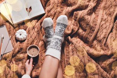 Image of Woman in warm socks resting on soft plaid, top view. Space for text