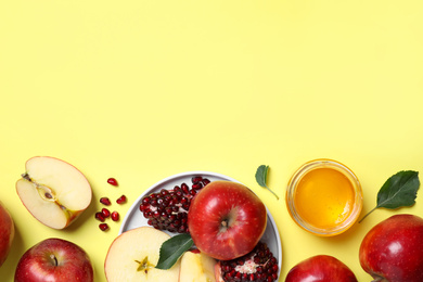 Photo of Honey, apples and pomegranate on yellow background, flat lay with space for text. Rosh Hashanah holiday