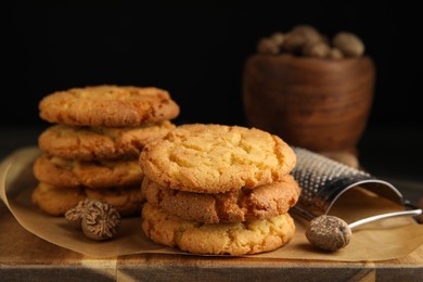 Photo of Tasty cookies, nutmeg seeds and grater on wooden board