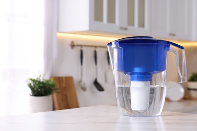 Photo of Water filter jug on white marble table in kitchen, closeup. Space for text