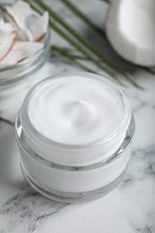 Photo of Jar of body cream with coconut on white marble table, closeup