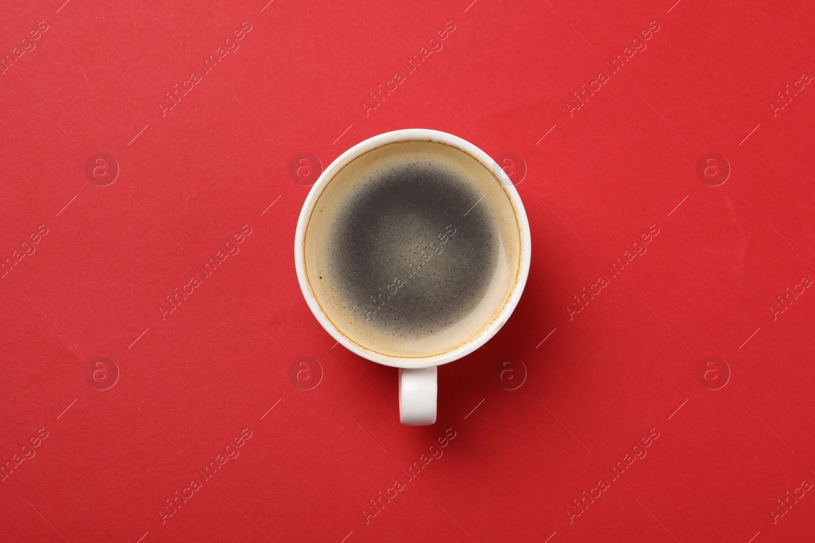 Photo of Aromatic coffee in cup on red background, top view