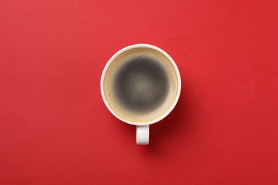 Aromatic coffee in cup on red background, top view